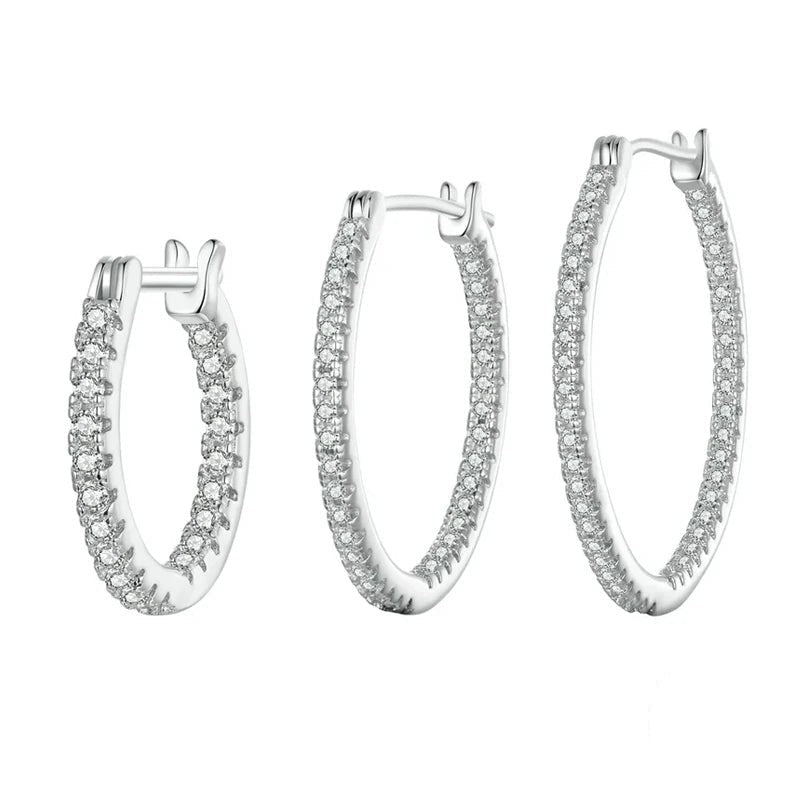Set of silver hoop earrings with clear gemstones on a white background