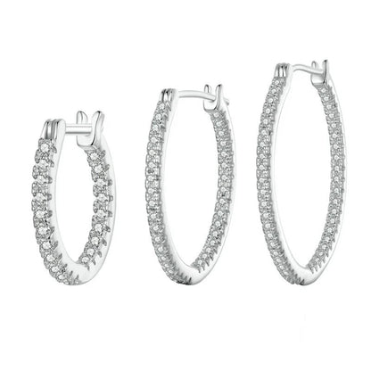 Set of silver hoop earrings with clear gemstones on a white background