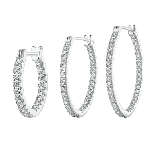 Set of silver hoop earrings with clear gemstones on a white background