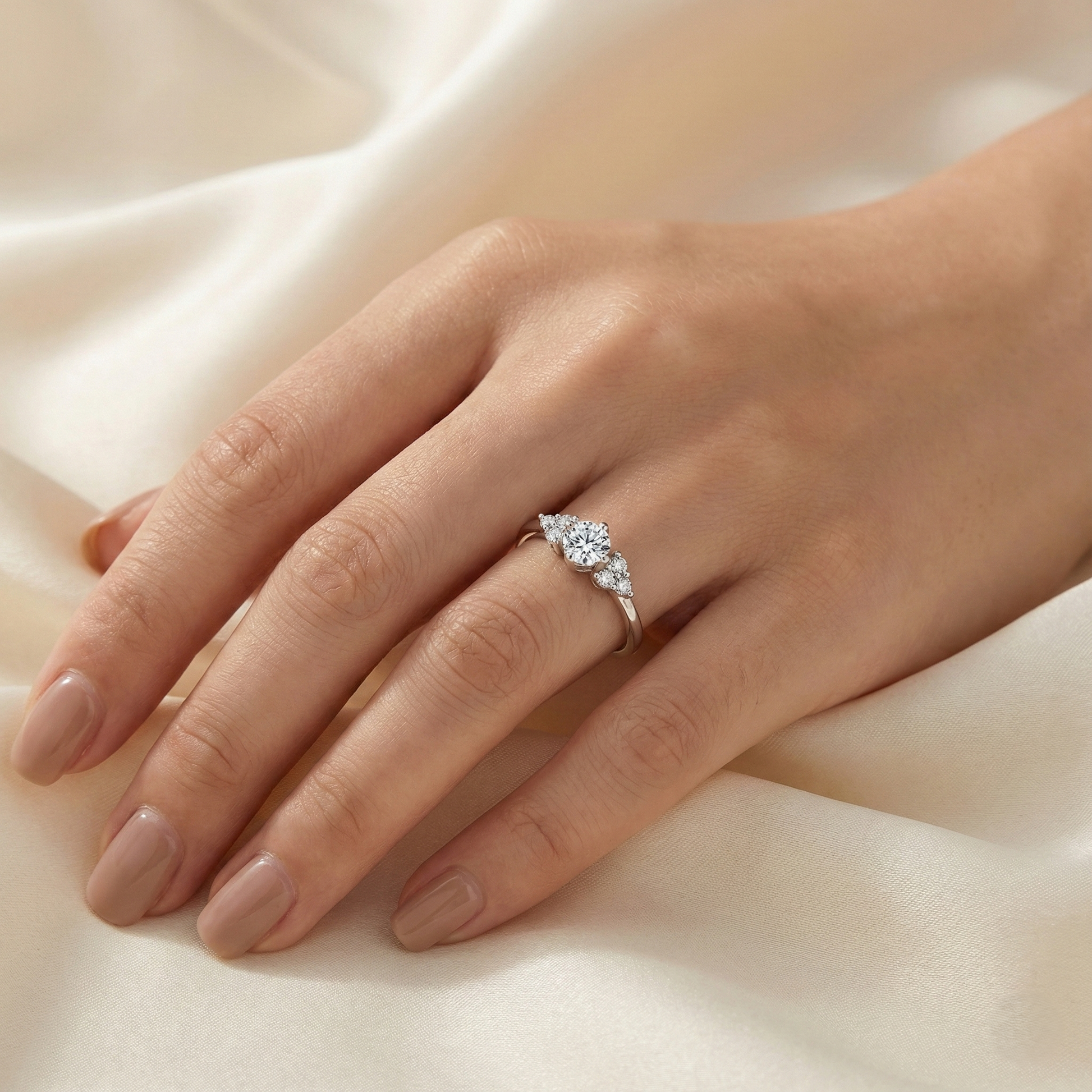 Hand wearing a diamond ring on a soft fabric background