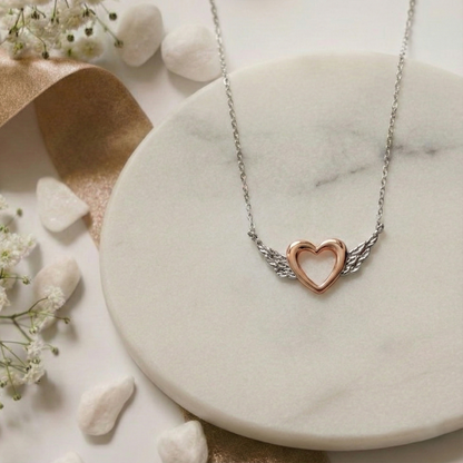 Heart-shaped necklace on a marble surface with flowers