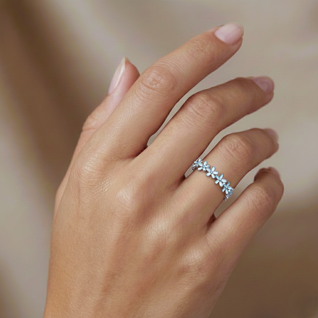 Close-up of a hand wearing a silver ring with small stones on a blurred background