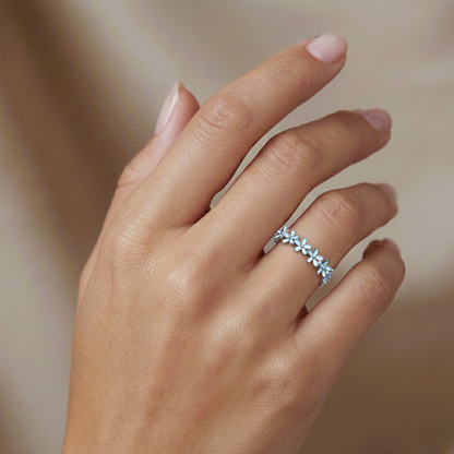 Close-up of a hand wearing a silver ring with small stones on a blurred background