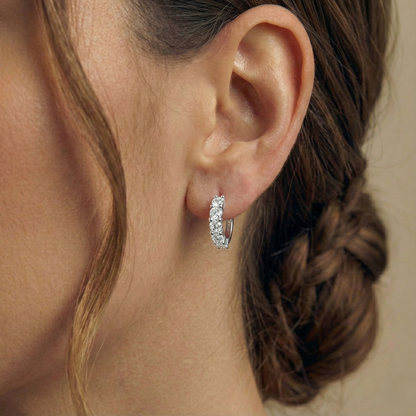 Close-up of an ear wearing a silver hoop earring with braided hair.