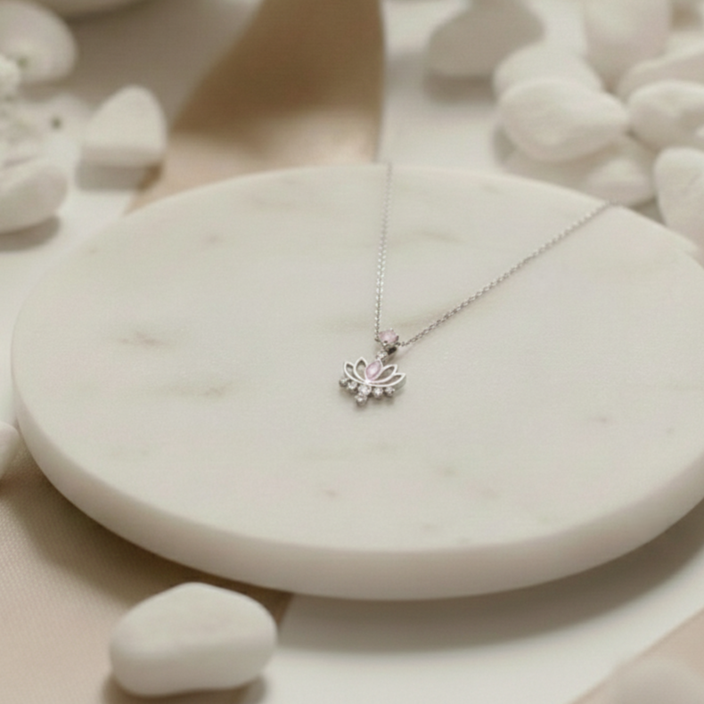 Silver necklace with a lotus flower pendant on a white stone surface