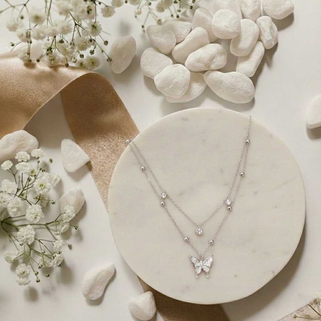 Butterfly necklace on a marble surface with flowers and stones
