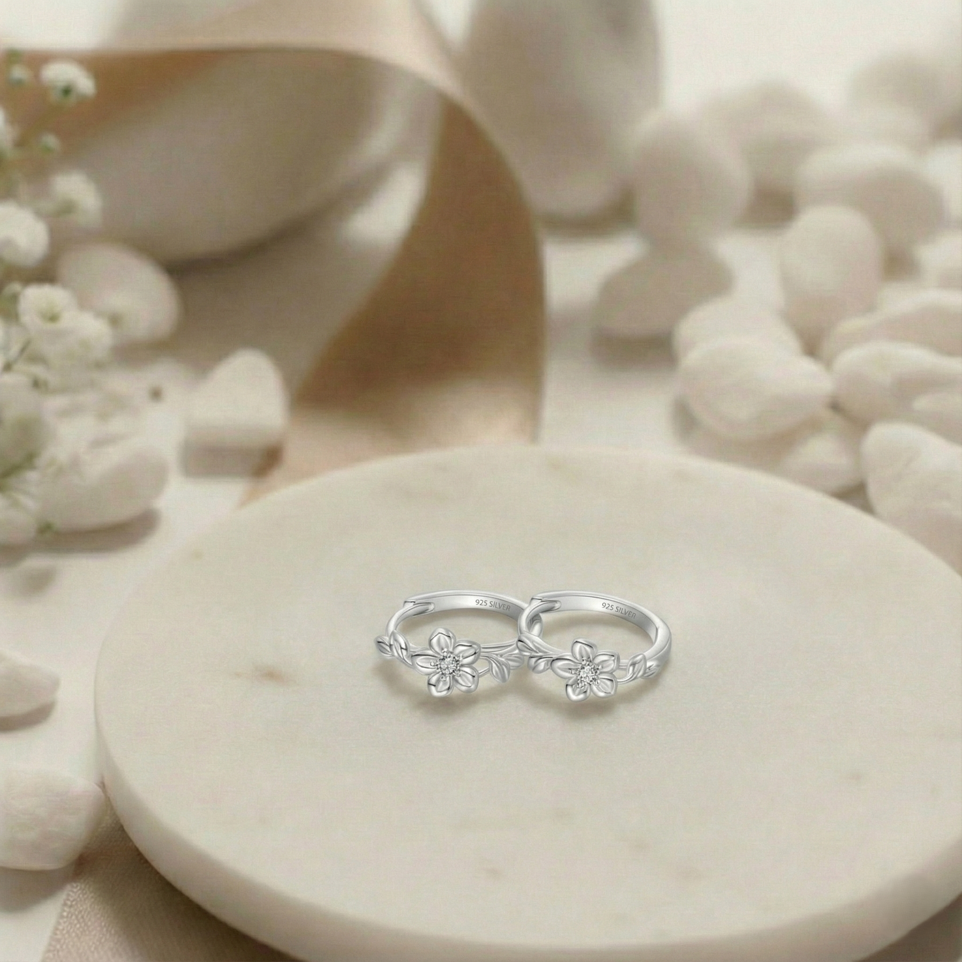 Silver ring with floral designs on a white stone surface