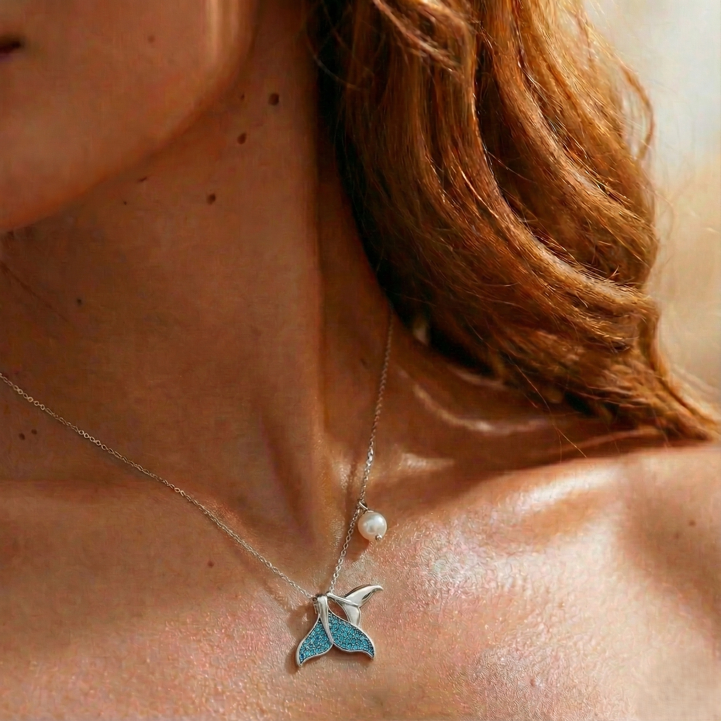 Necklace with a blue pendant and pearl on a person's neck