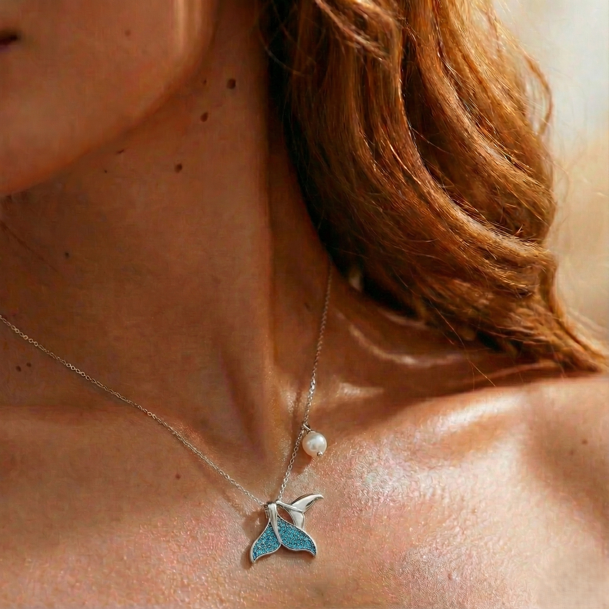 Necklace with a blue pendant and pearl on a person's neck