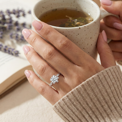 Hand holding a mug of tea with a decorative ring on a blurred background