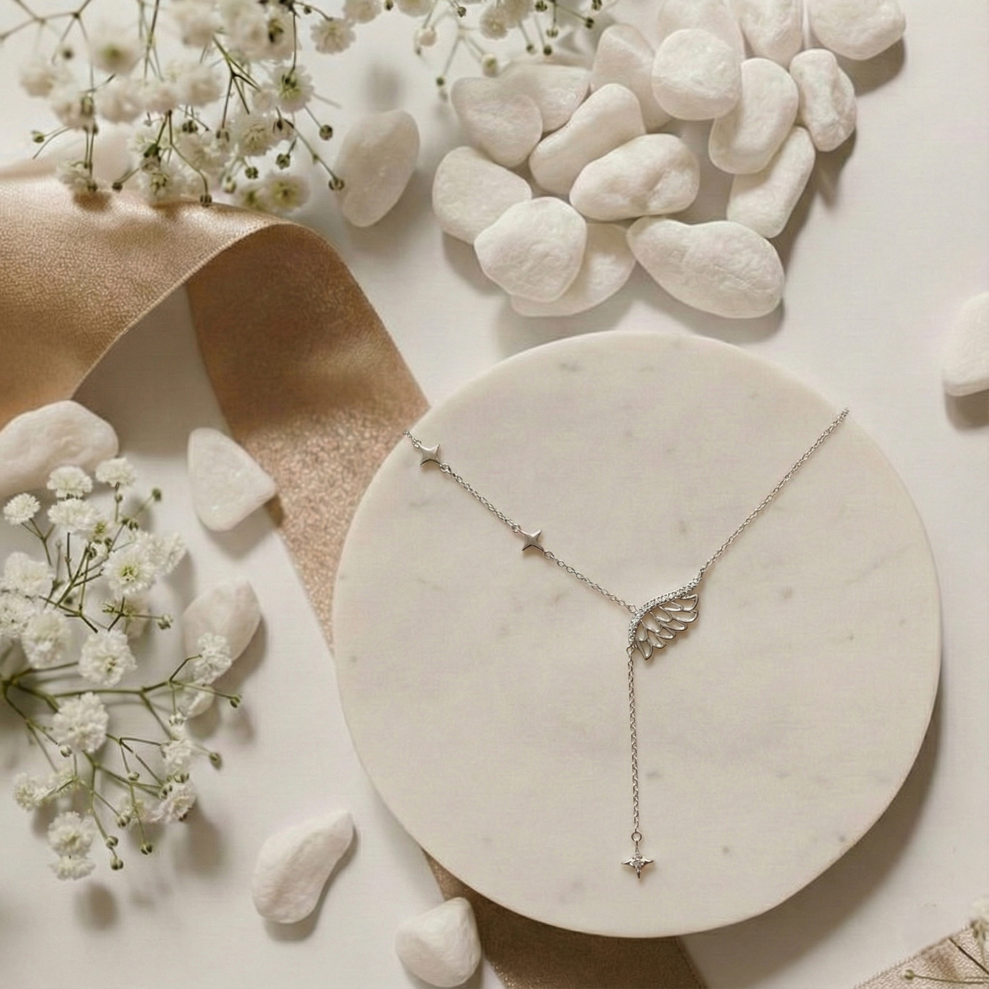 Silver necklace on a marble surface with white flowers and stones