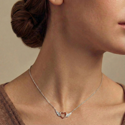 Necklace with a heart and wing pendant worn by a person