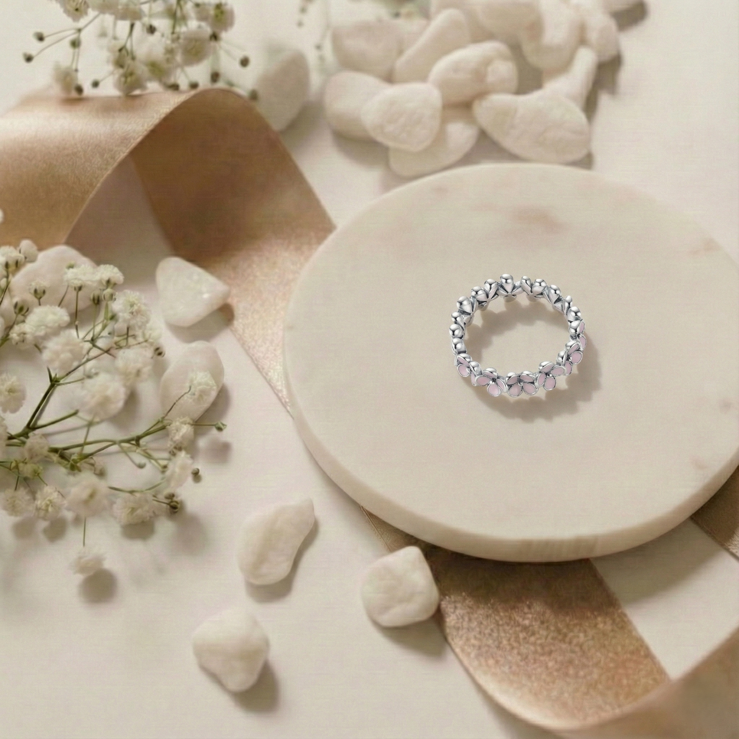 Silver ring on a stone surface with small stones and flowers