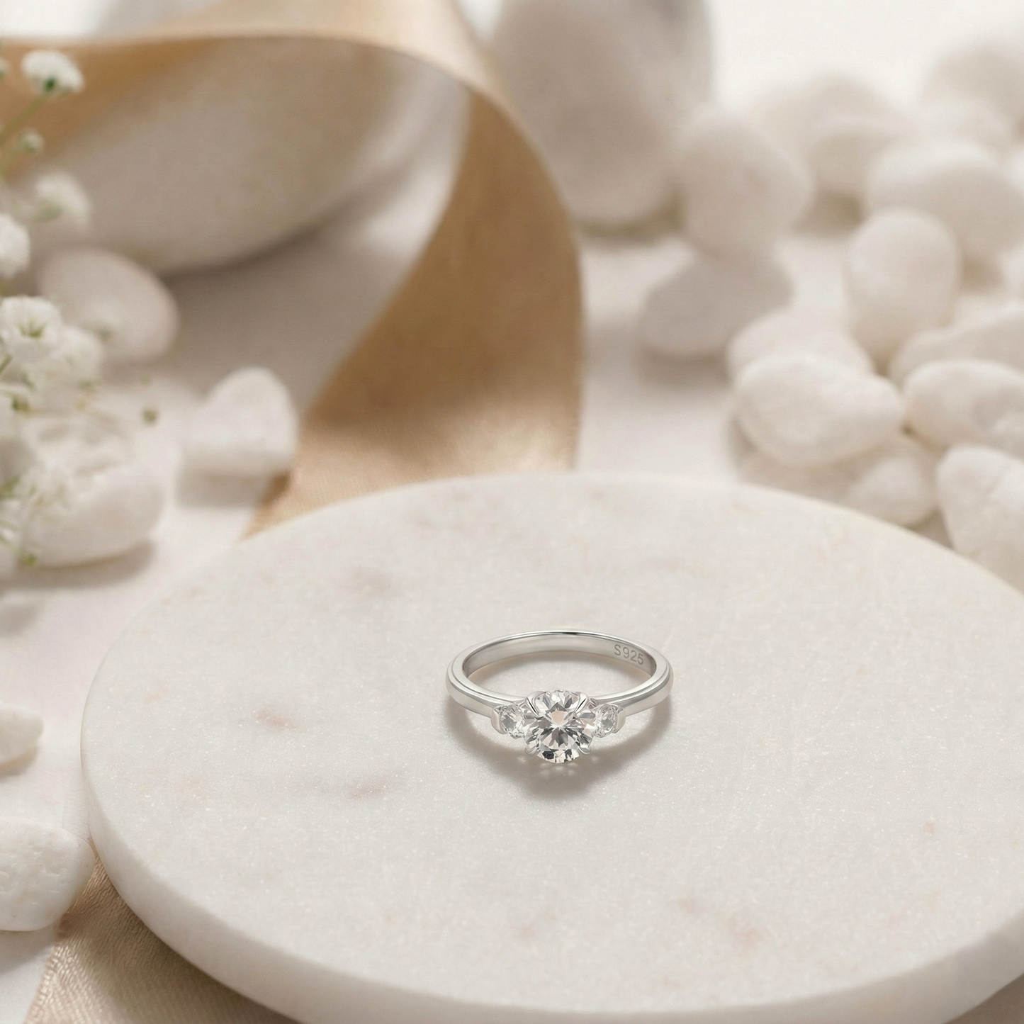 Silver ring on a white stone with flowers and shells in the background