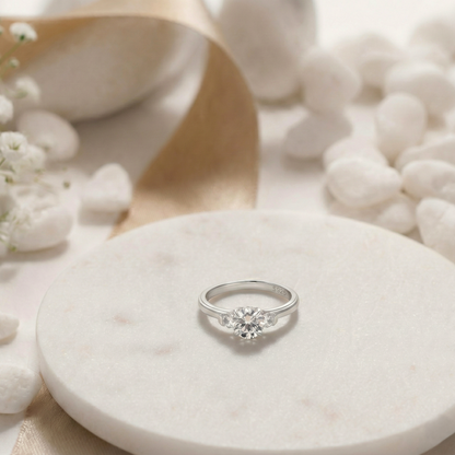 Silver ring on a white stone with flowers and shells in the background