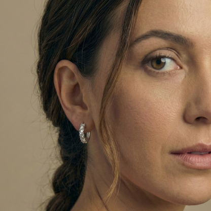 Close-up of a woman wearing a diamond earring against a neutral background
