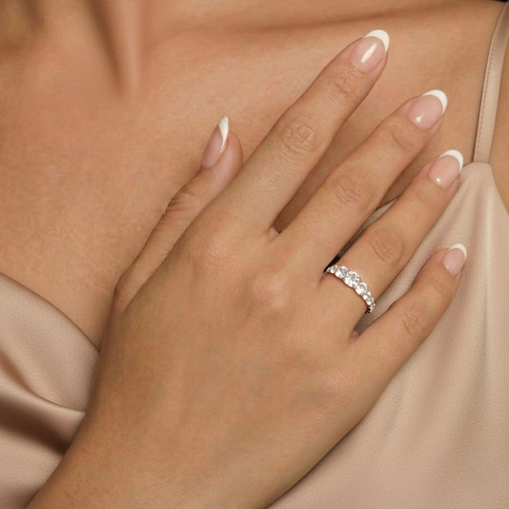 Hand wearing a silver ring with a diamond on a neutral background
