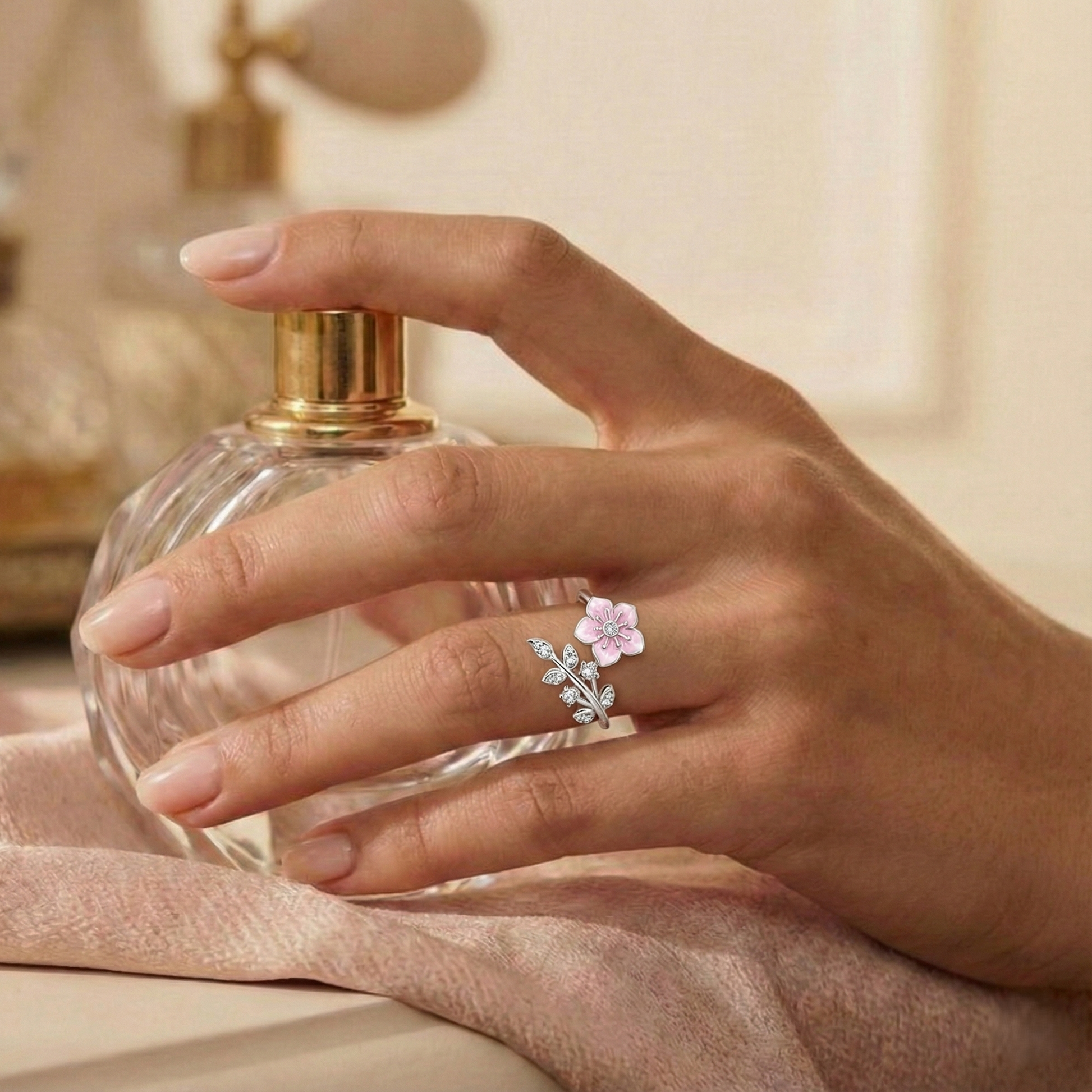 Hand holding a perfume bottle with a floral ring on a soft background