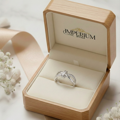 Silver ring in a wooden box with 'Imperium Jewels' branding, surrounded by white flowers.