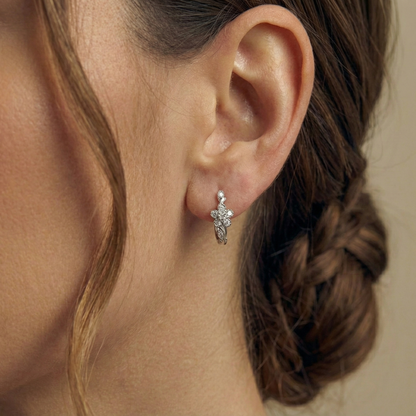 Close-up of an ear wearing a silver earring with braided hair.