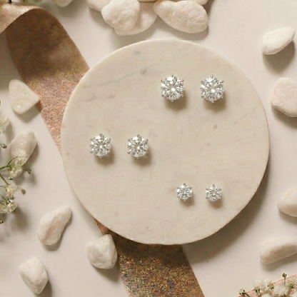 Silver earrings on a marble surface with stones and flowers
