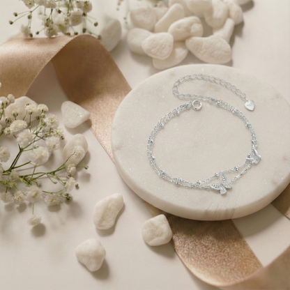 Silver bracelet on a marble surface with white flowers and stones