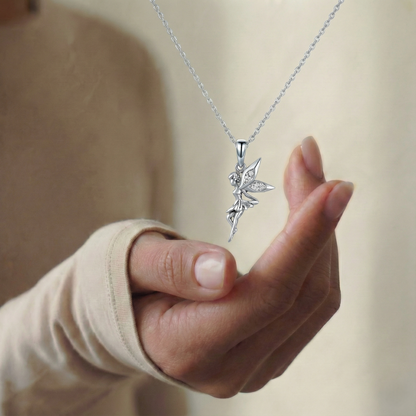 Hand holding a silver necklace with a leaf-shaped pendant against a neutral background