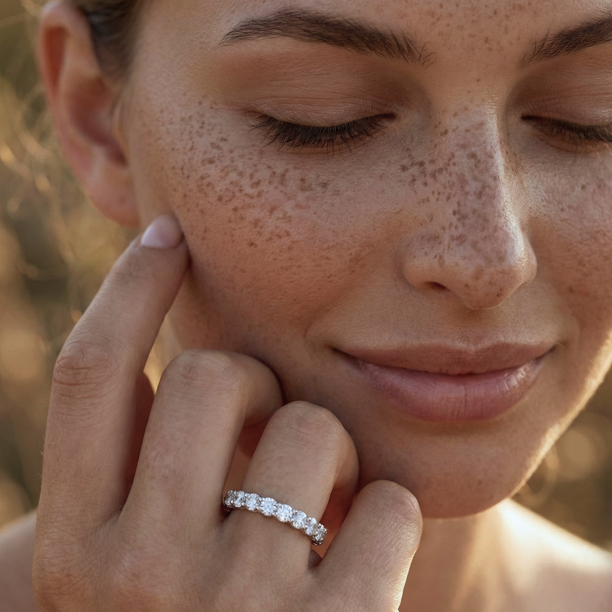 Close-up of a woman's face with freckles, wearing a diamond ring on her finger.