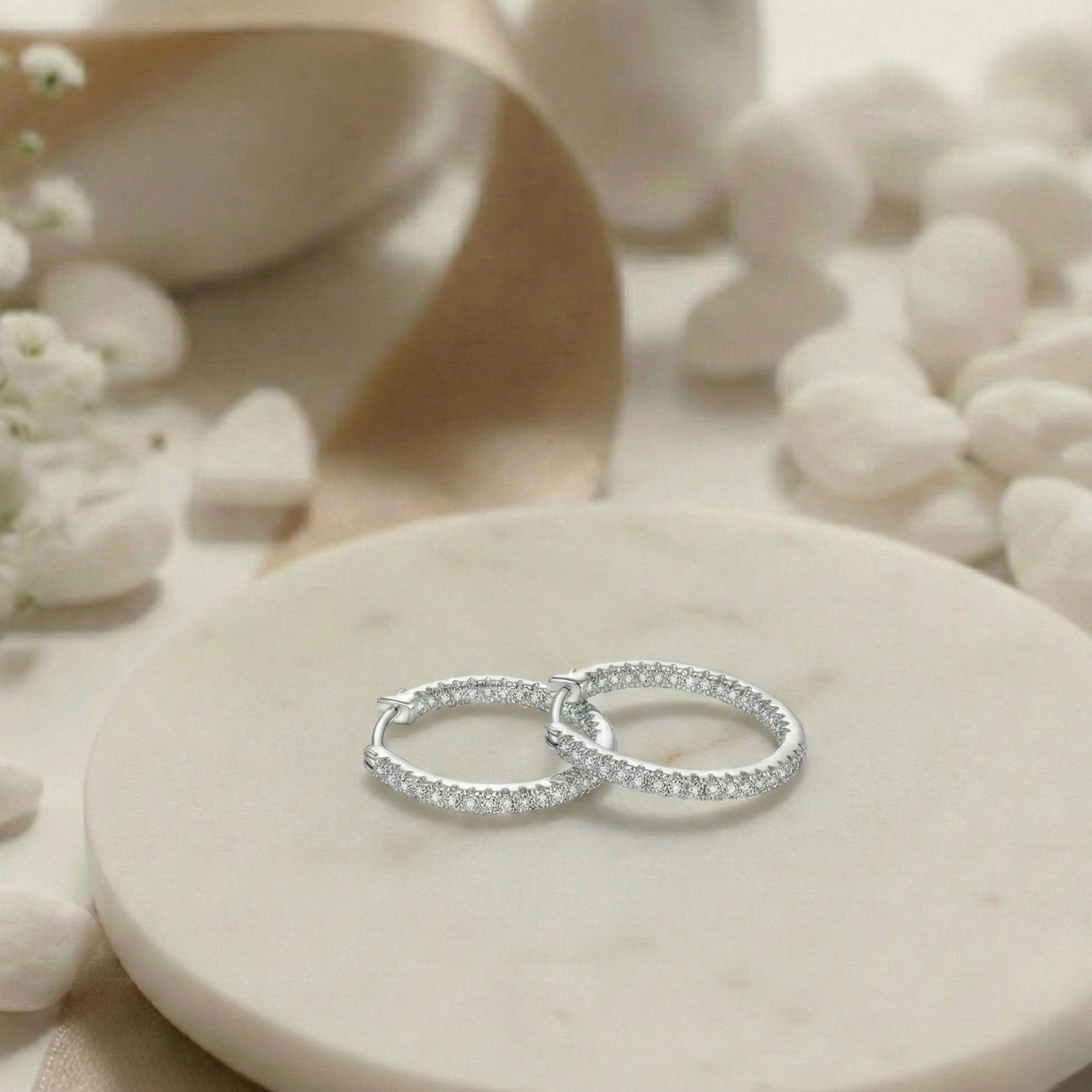 Silver ring with small diamonds on a stone surface with white flowers and shells.