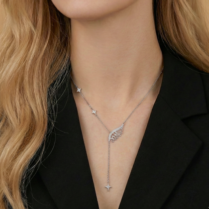 Silver necklace with a wing pendant worn by a person with blonde hair.