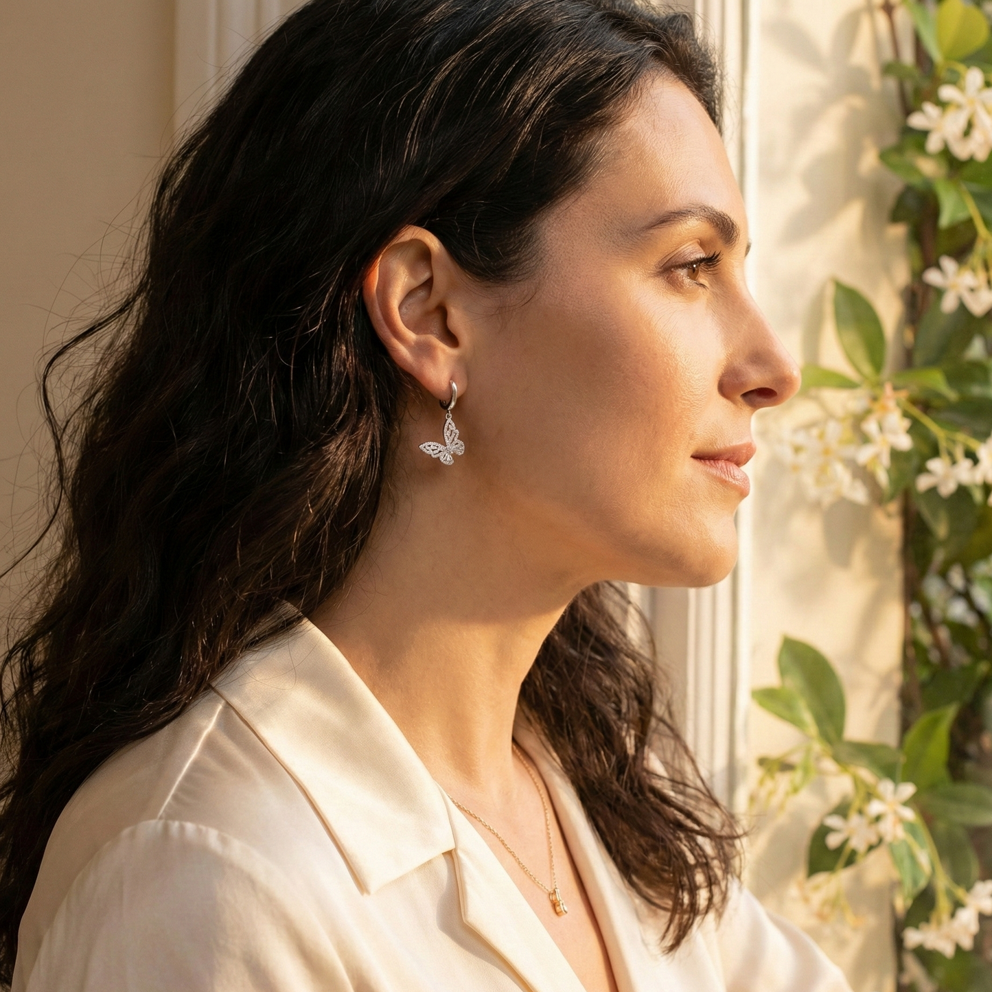 Woman wearing earrings with a window and flowers in the background