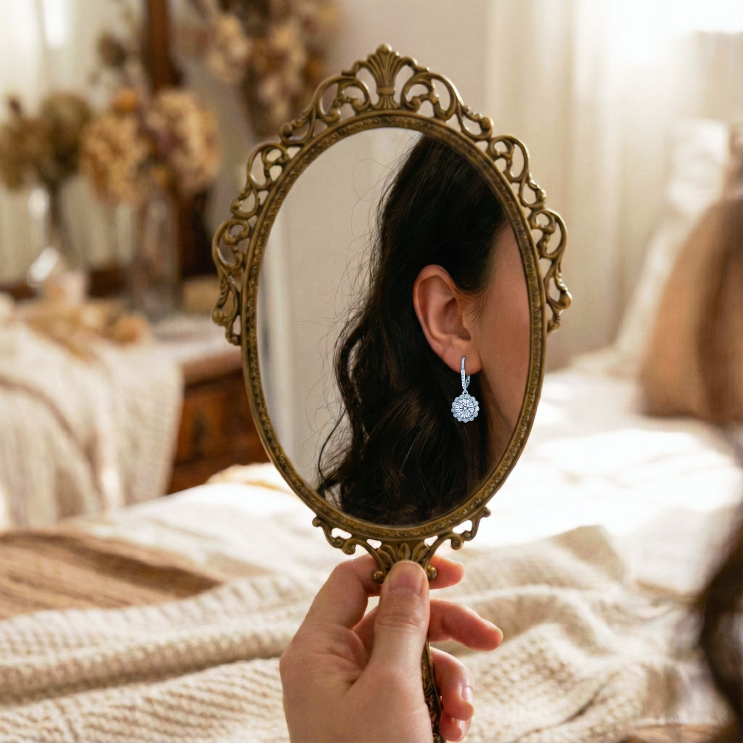 Person holding a vintage-style mirror to check earrings in a cozy room.