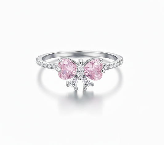 Silver ring with pink gemstone bow design on a white background