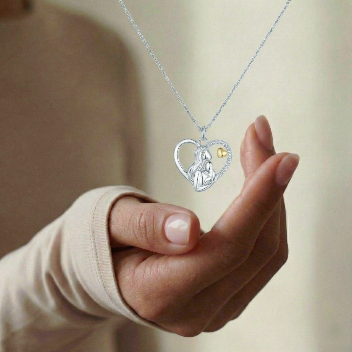 Hand holding a necklace with a heart-shaped pendant featuring a small gold heart.