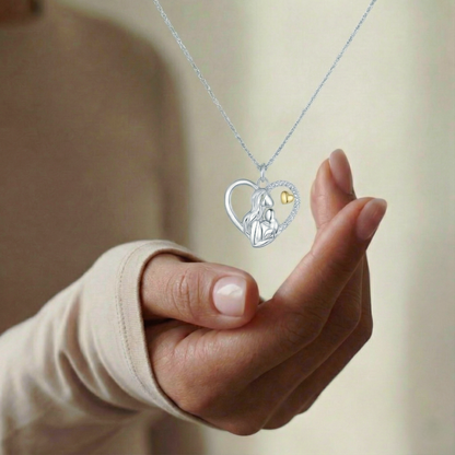 Hand holding a necklace with a heart-shaped pendant featuring a small gold heart.