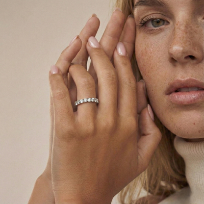 Close-up of a woman's hand wearing a diamond ring with a neutral background